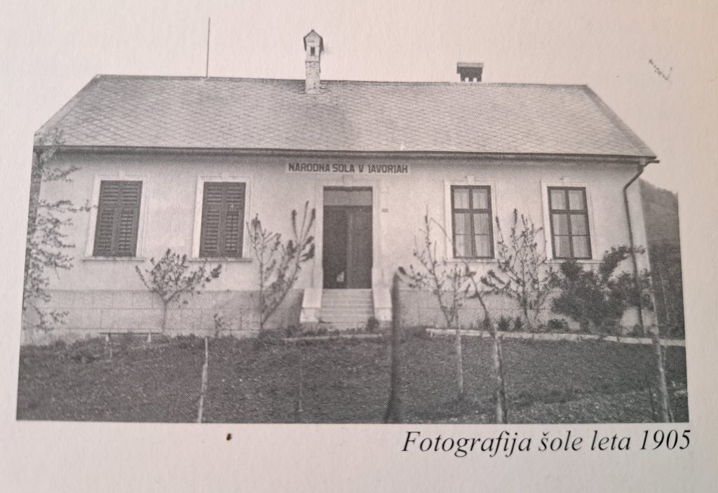 Črnobela fotografija prikazuje zunanjost šole v Javorjah iz leta 1905.